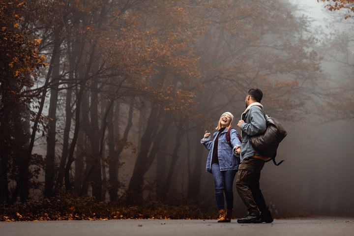 Image of two people laughing and walking in the woods.